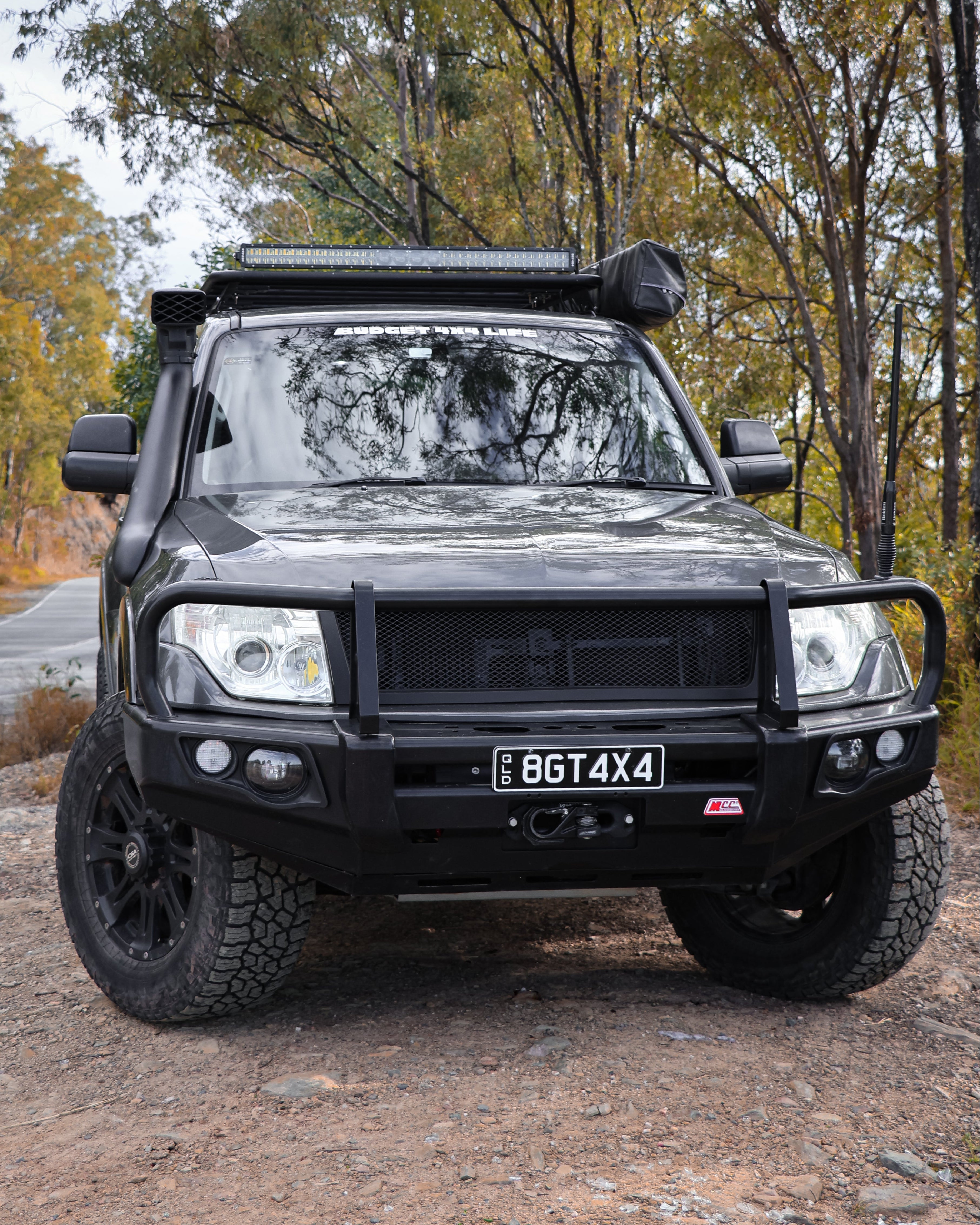 Black off-road vehicle on a dirt road with trees in the background