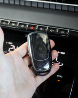 Hand holding a car key fob in front of a car's climate control panel.
